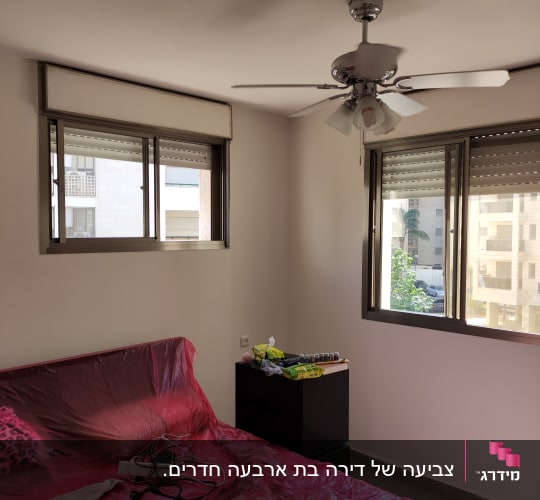 חדר עם מיטה מכוסה בניילון אדום, צבעים על שידה